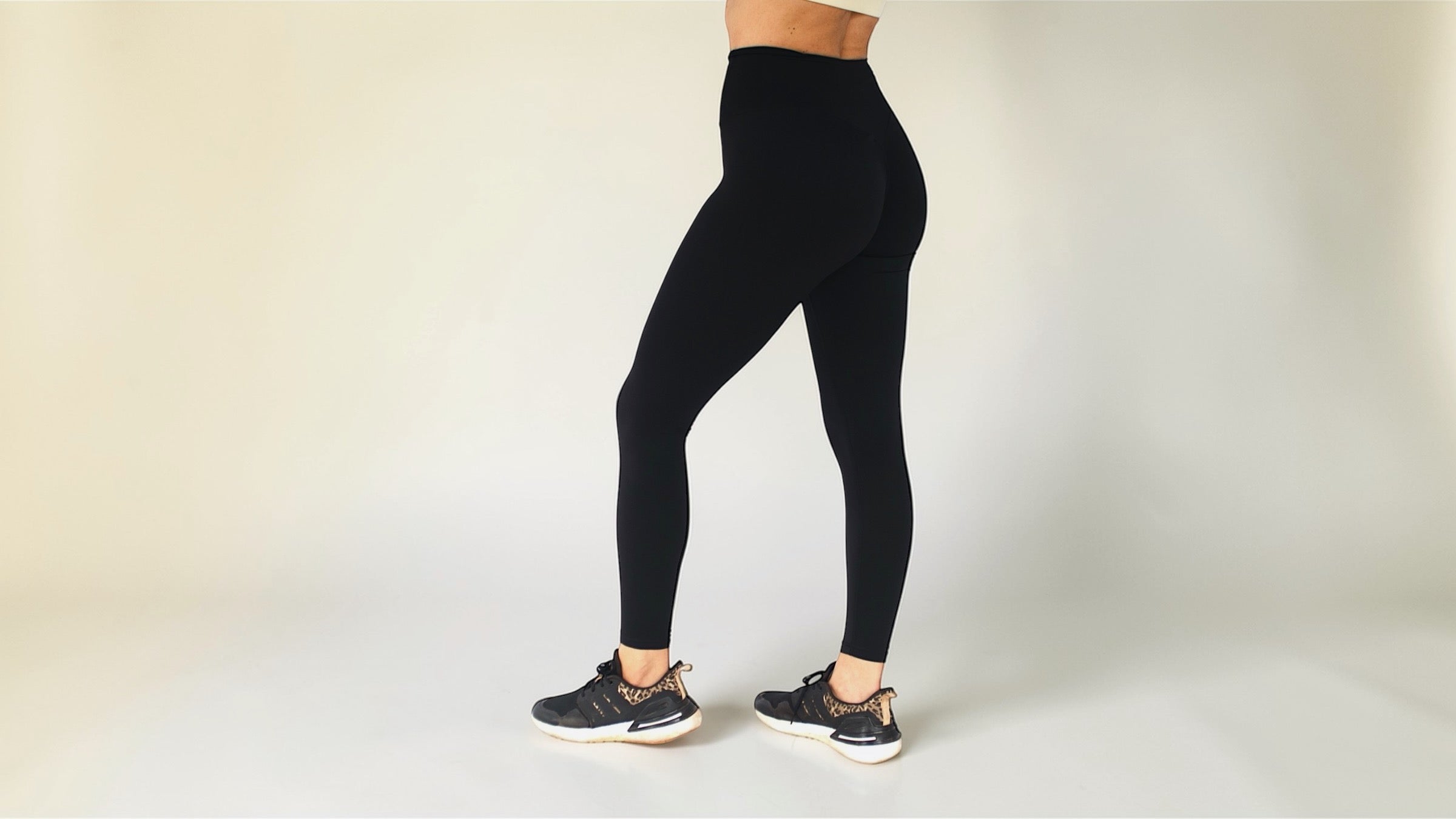 Person wearing black leggings on a plain background