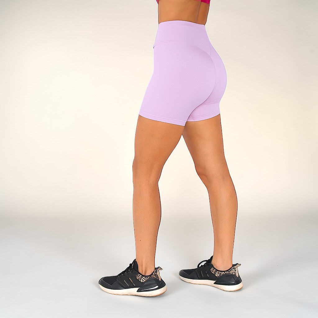 Person wearing light purple high-waisted shorts on a plain background