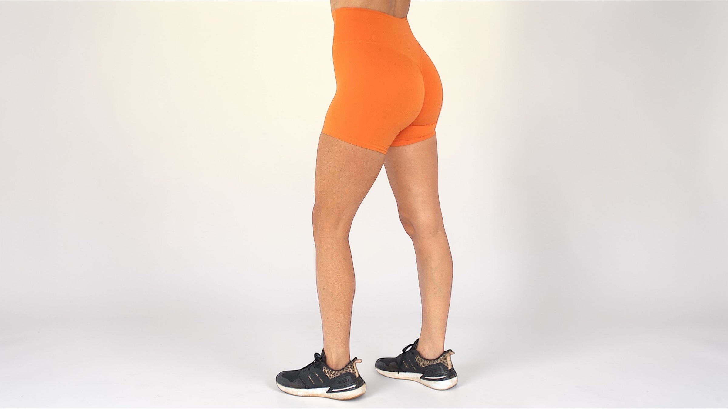 Person wearing bright orange athletic shorts on a white background