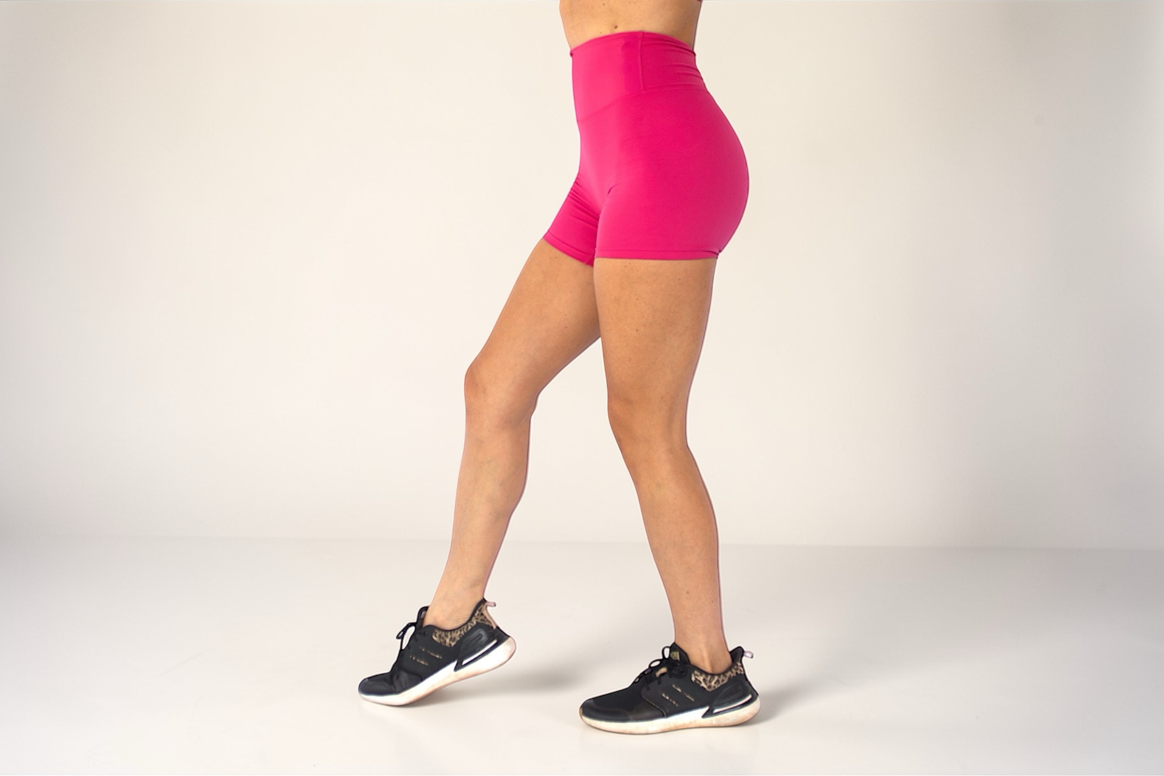 Person wearing bright pink athletic shorts on a plain background