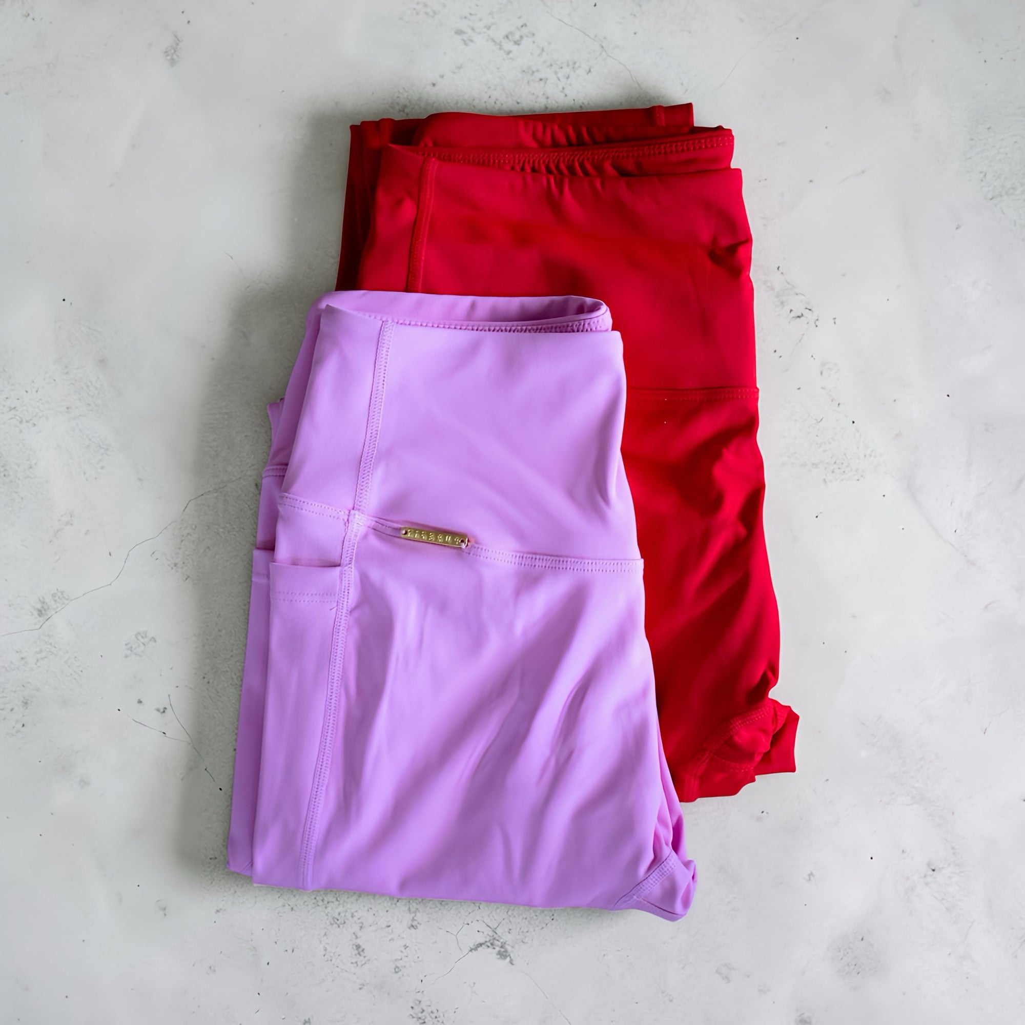 Folded purple and red pants on a light gray surface