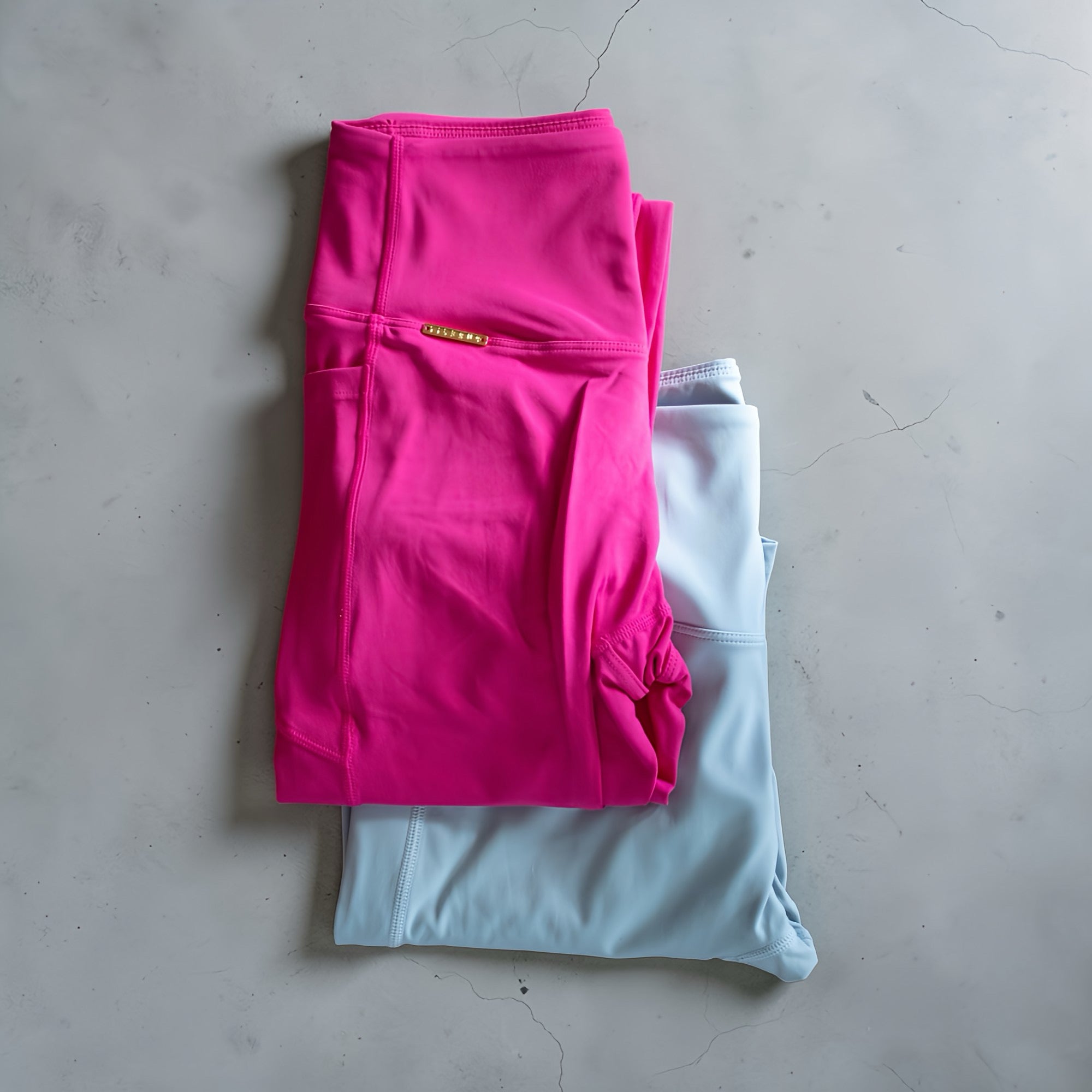 Folded pink and light blue leggings on a gray surface