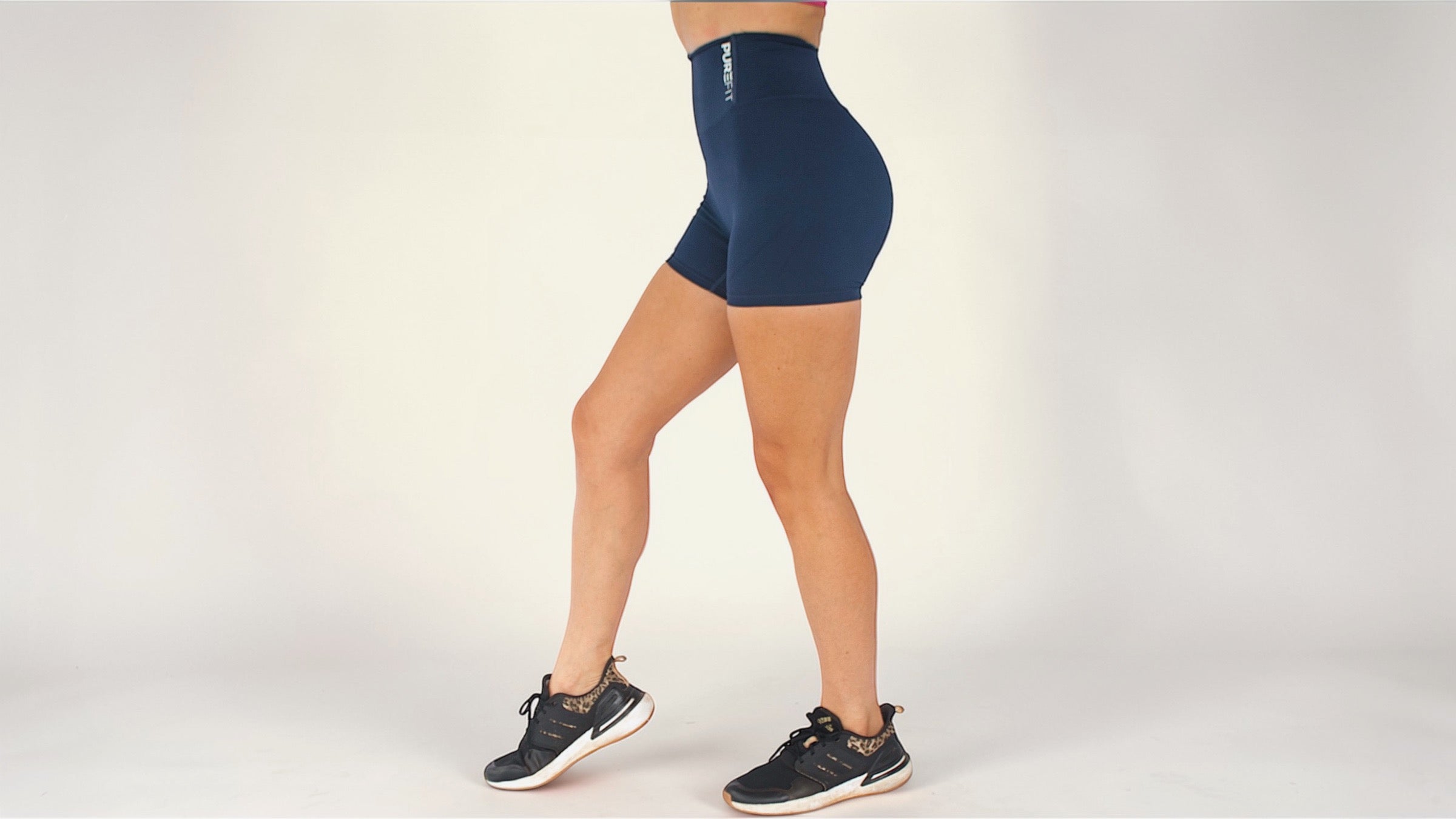 Person wearing navy blue athletic shorts on a plain background