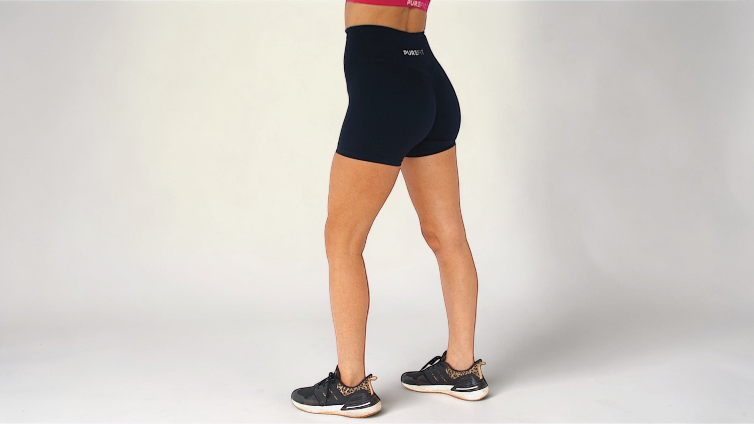 Person wearing black athletic shorts on a plain background