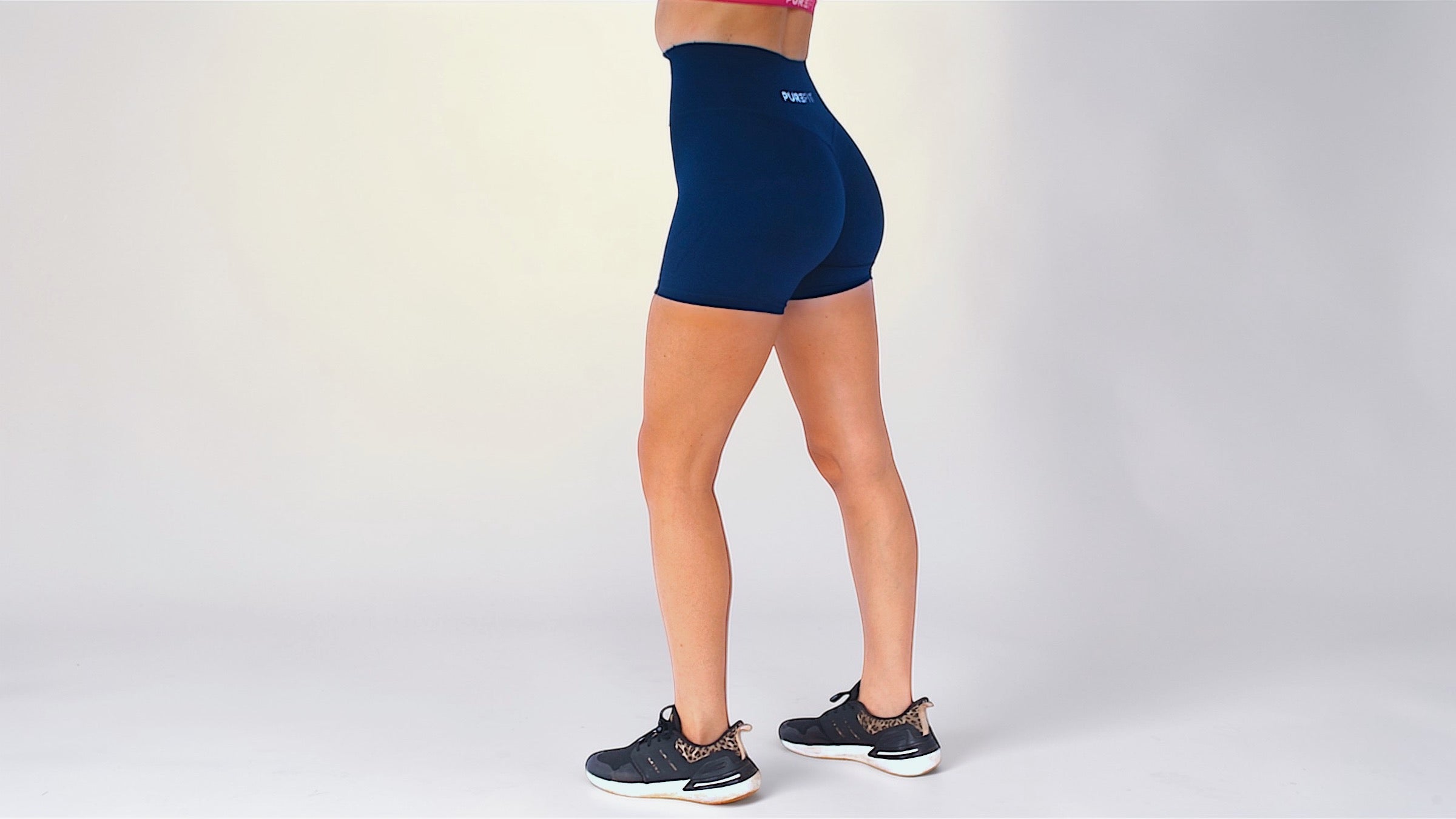 Person wearing navy blue athletic shorts on a light gray background
