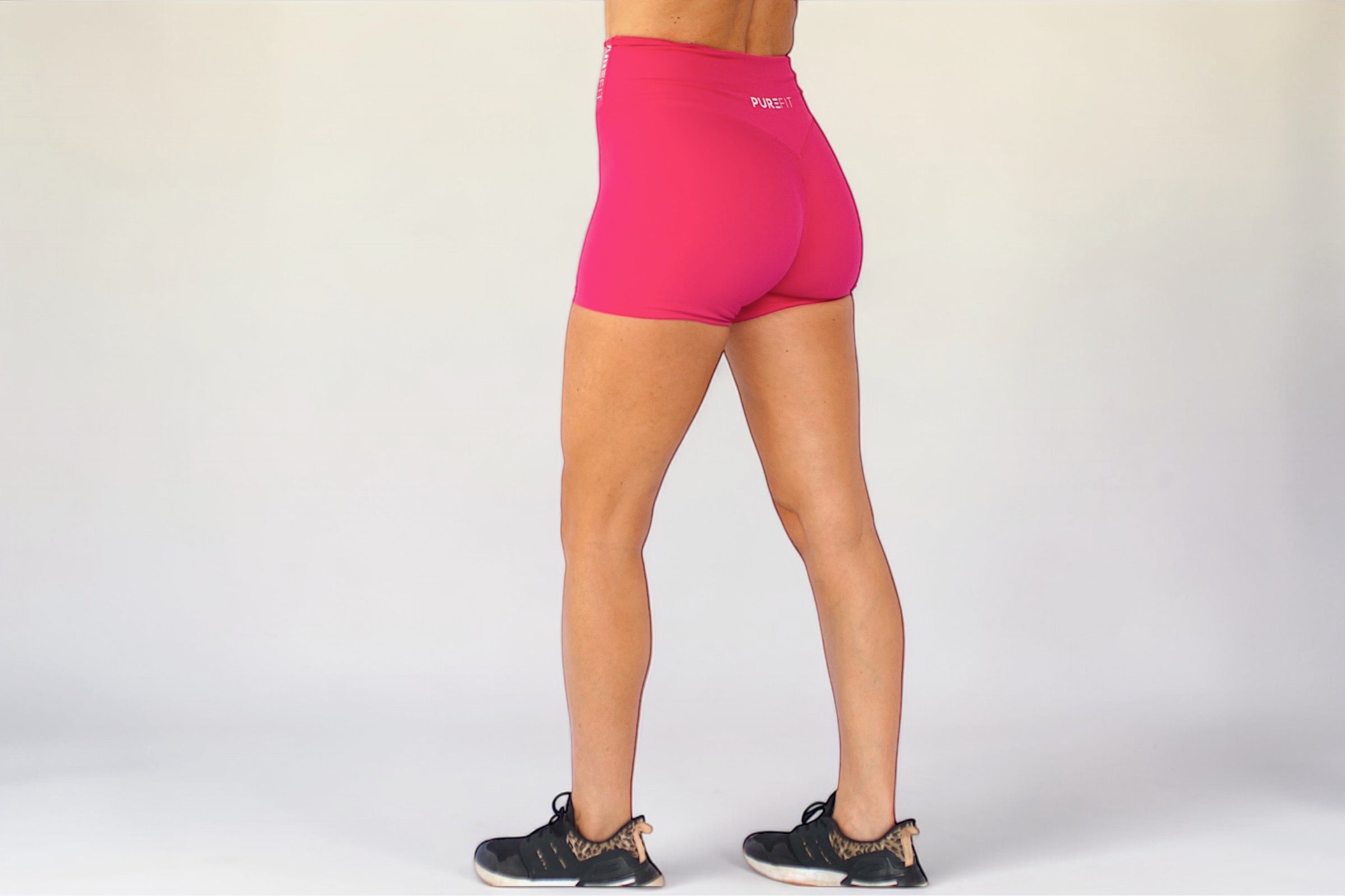 Person wearing bright pink athletic shorts on a white background