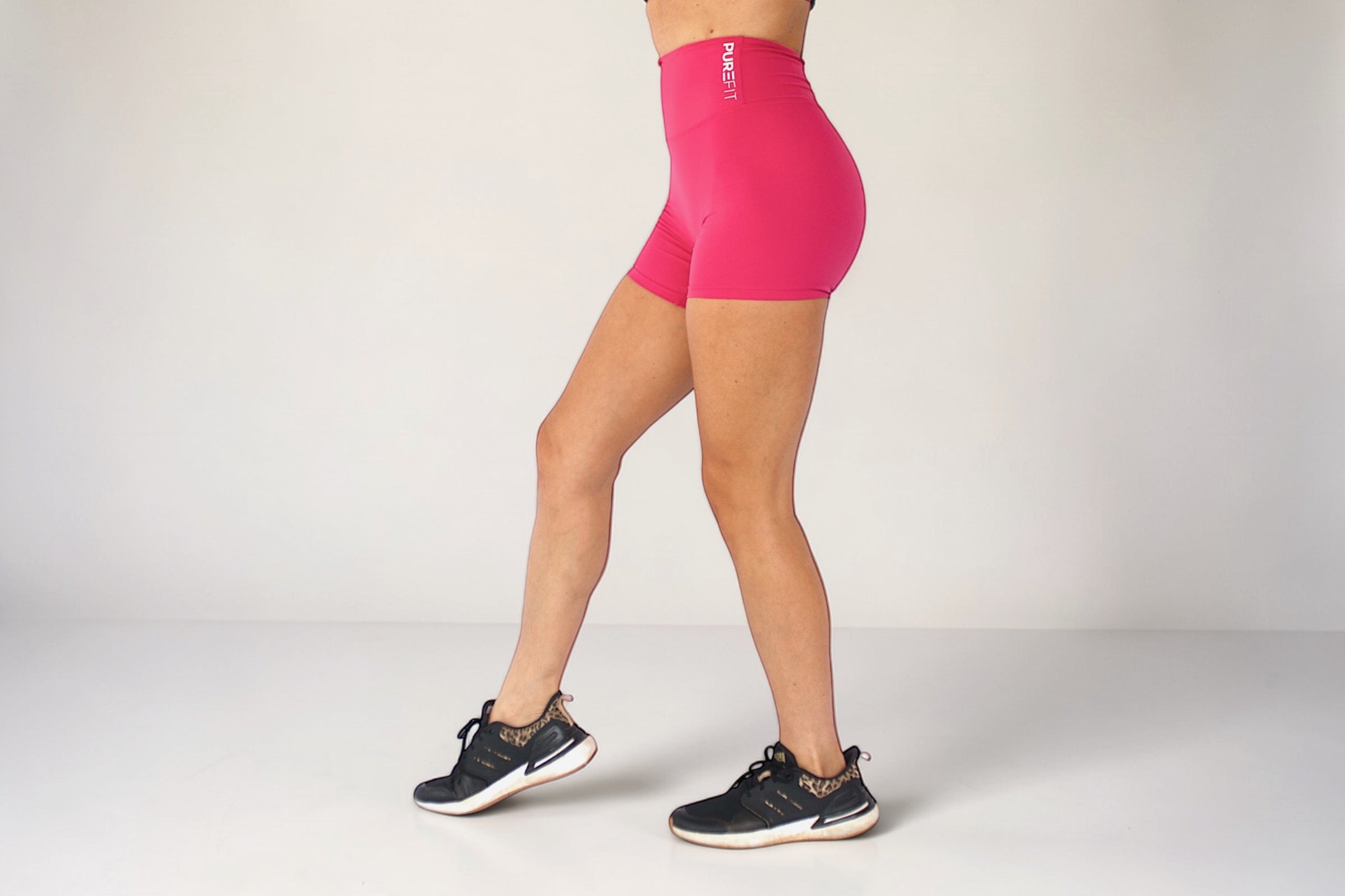 Person wearing pink athletic shorts on a plain background