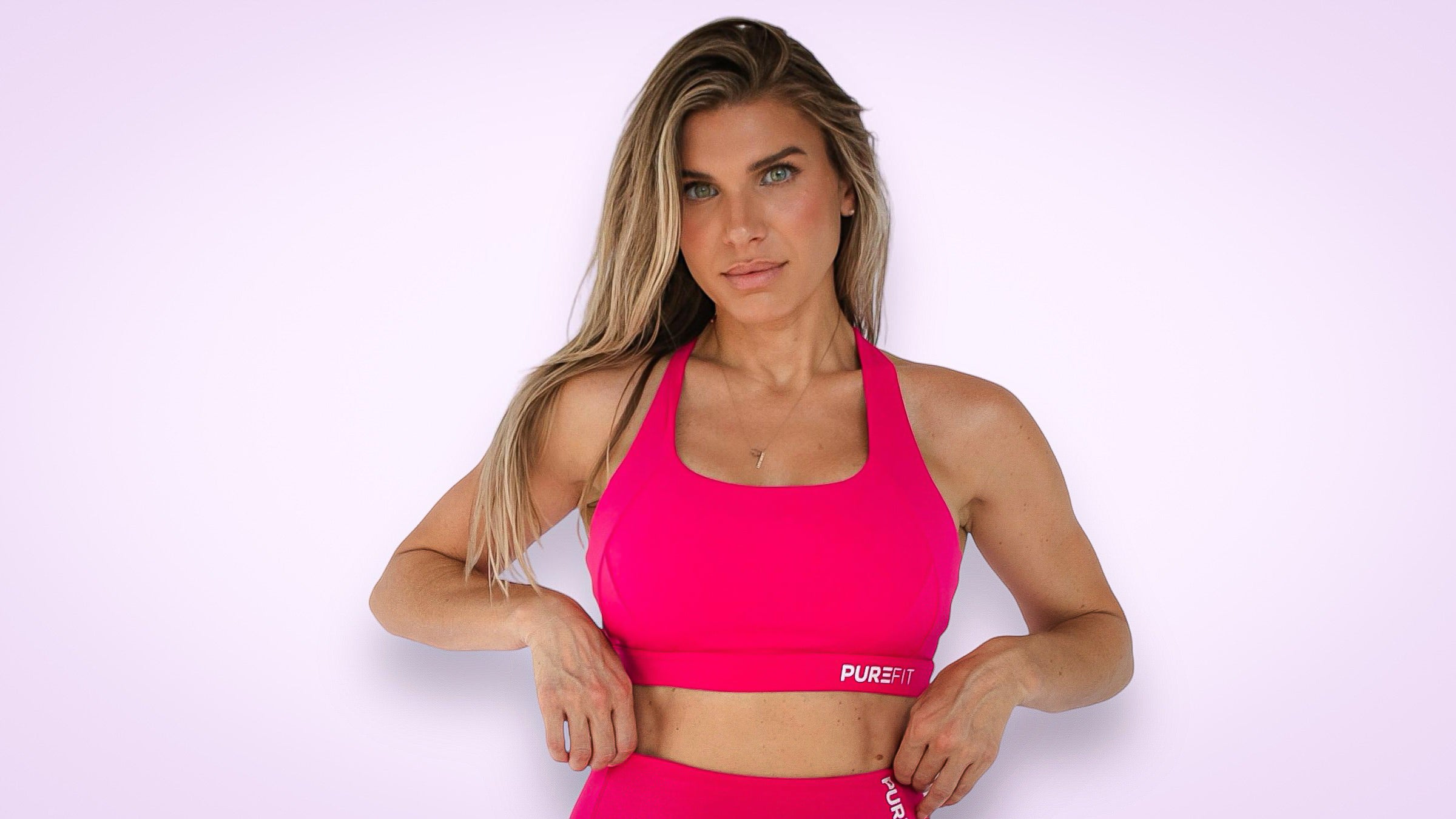women modeling a hot pink sports bra standing in front of a neutral background.
