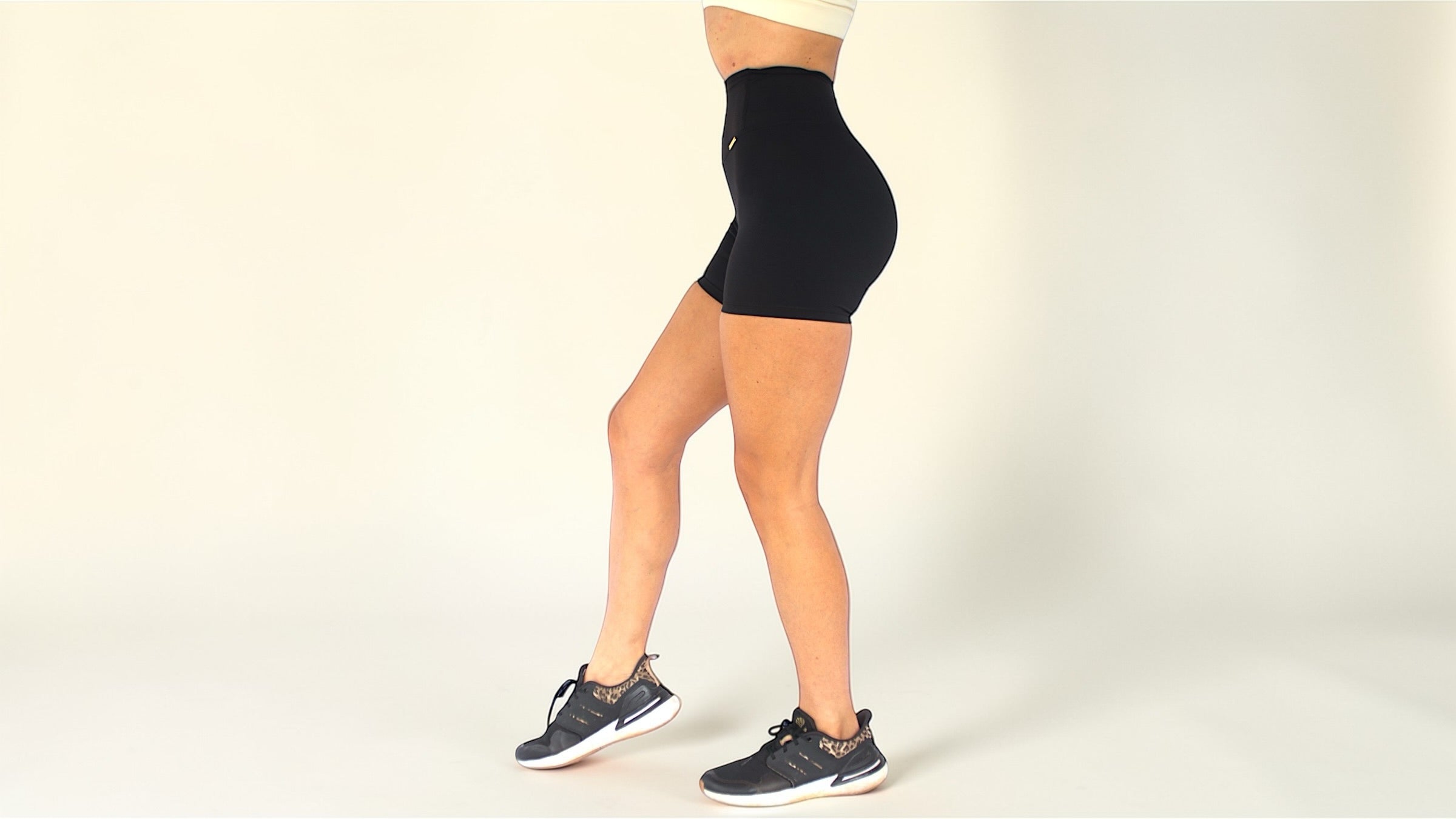 Person wearing black high-waisted shorts on a plain background