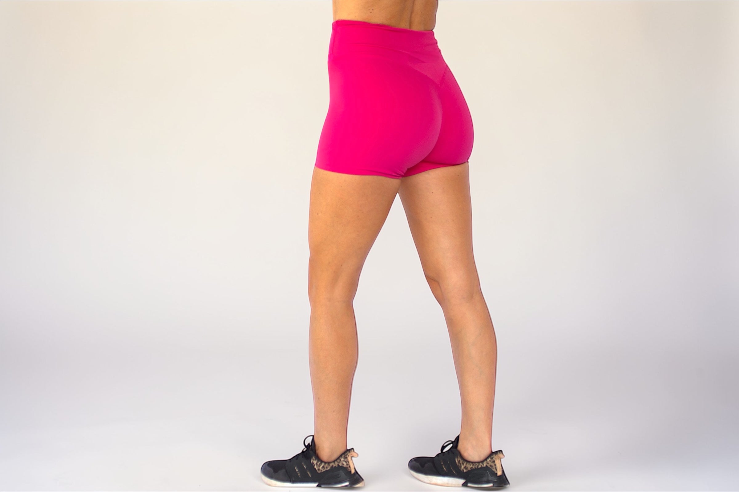 Person wearing bright pink athletic shorts on a white background